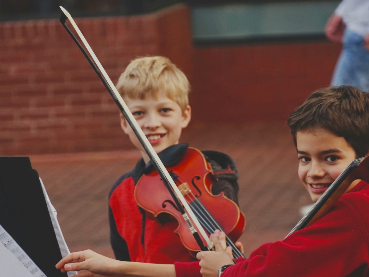 Young violin student learning alongside a young cello player