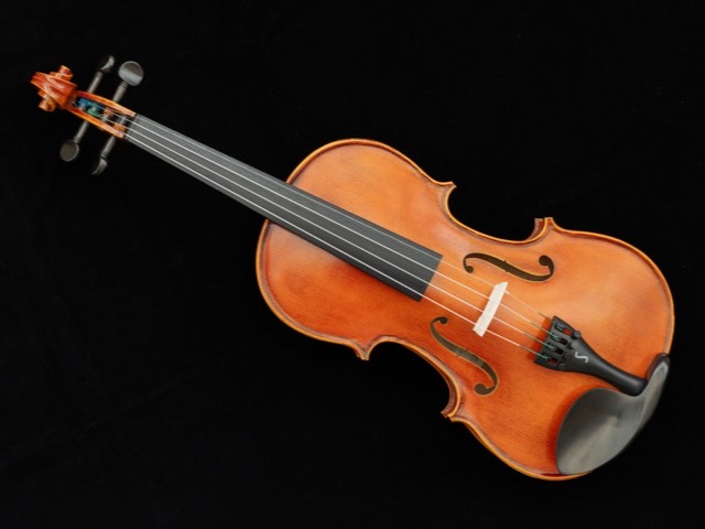 A violin viewed from above against a black background, showing its scroll, fingerboard, and body.